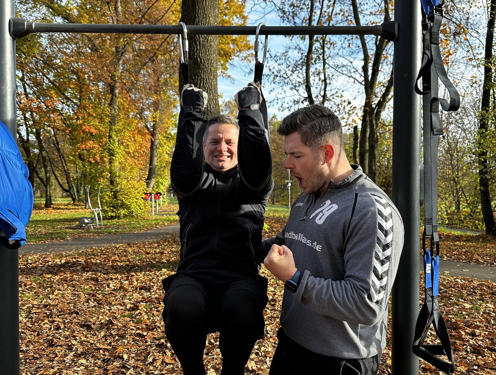 Outdoor personal training – coach encouraging a client through a pull-up
