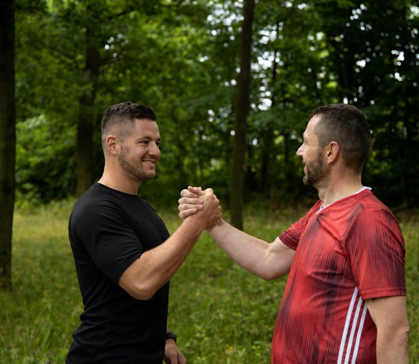 Wolf Hagen with a client after training, shaking hands in the woods